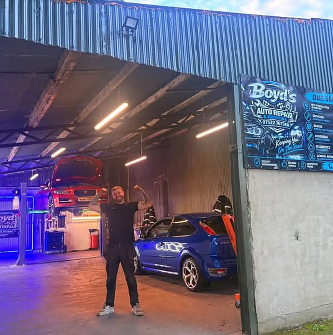 Mark flexing in the open door of his unit, with a blue Focus ST inside and the Boyd's sign on the wall